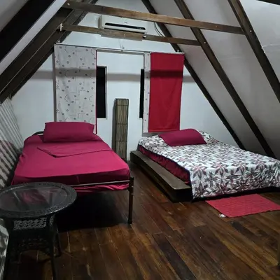 a attic room with two beds and a table at Congos Hostal y Camping in Playa Hermosa
