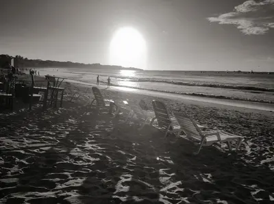 a group of chairs sitting on a beach with the sun at Hotel La Palapa in Tamarindo