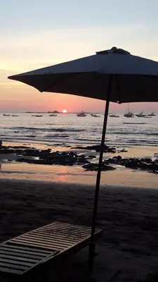 an umbrella sitting on a beach with the ocean at Hotel La Palapa in Tamarindo