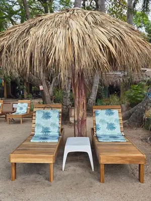 two benches sitting under a straw hut at Hotel La Palapa in Tamarindo
