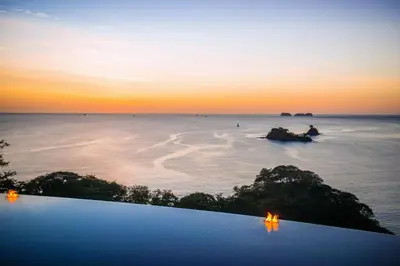 a pool with a view of the ocean at sunset at Casa Chameleon Hotel Las Catalinas - Adults Only in Playa Flamingo