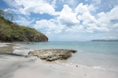 a beach with a rock in the water at Oceanview Studio Apartment with Community Pool & Views of Flamingo Marina in Playa Flamingo