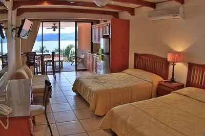 a bedroom with two beds and a kitchen with a view at Oceanview Studio Apartment with Community Pool & Views of Flamingo Marina in Playa Flamingo