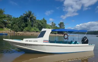a white boat with a blue canopy on the water at Life for Life Hostel Lodge Drake Bay Home of Sea Turtle Marine Conservation Project Osa Peninsula near San Josecito Beach in Drake