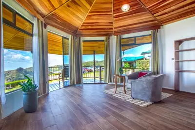 a living room with wood ceilings and large windows at Hotel Trópico Monteverde in Monteverde Costa Rica