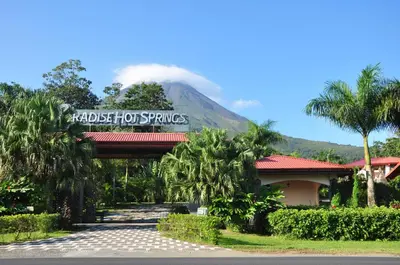 a hotel with a sign in front of a mountain at Paradise Hot Springs - Thermal Water & Volcano Views in Fortuna