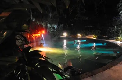 a pool at night with people swimming in it at Paradise Hot Springs - Thermal Water & Volcano Views in Fortuna