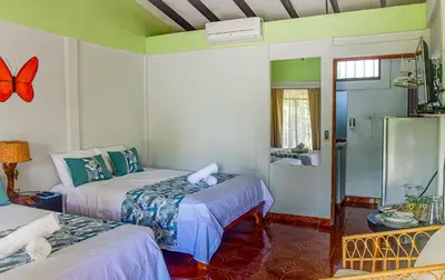 a bedroom with two beds and a bathroom with a shower at Cabinas Bahía Uvita - Marino Ballena National Park Lodge in Uvita