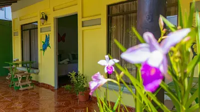 a yellow house with purple flowers in the foreground at Cabinas Bahía Uvita - Marino Ballena National Park Lodge in Uvita