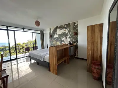 a bedroom with a bed and a large window at Sunshine Sanctuary Boutique Jungle Lodge in Montezuma