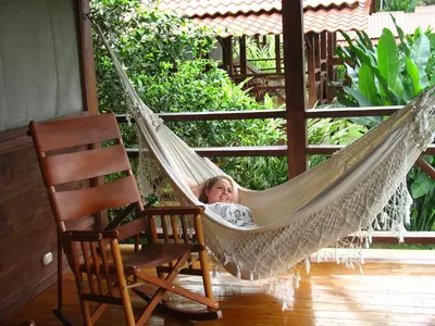 a little girl laying in a hammock on a porch at La Anita Rain Forest in Colonia Dos Ríos