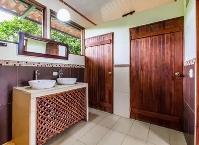 a bathroom with two sinks and a wooden door at La Anita Rain Forest in Colonia Dos Ríos