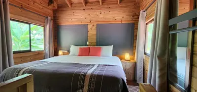 a bedroom with a bed in a wooden cabin at Boutique Hotel y Spa Tangara Azul in Ojochal