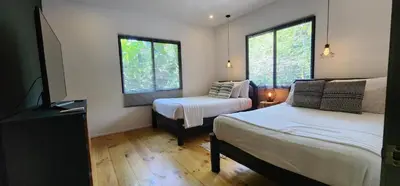 a room with two beds and a tv and two windows at Boutique Hotel y Spa Tangara Azul in Ojochal