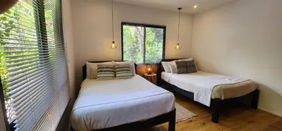 two beds in a small room with a window at Boutique Hotel y Spa Tangara Azul in Ojochal