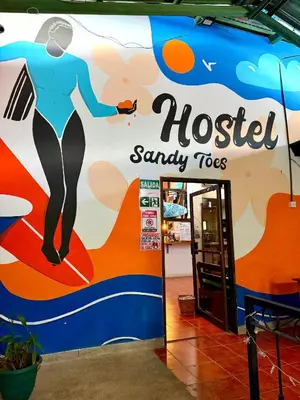 a sign for a hostess sandy toes store at Sandy Toes Hostel in Sámara