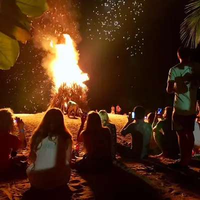 people sitting on the beach watching a fire show at Sandy Toes Hostel in Sámara