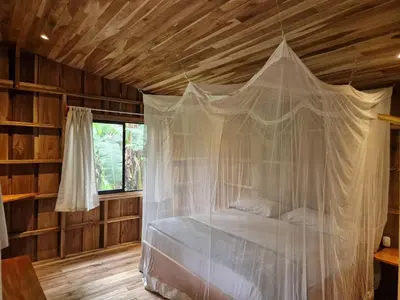 a bedroom with a bed with a mosquito net at Finca Amistad Cacao Lodge in Bijagua
