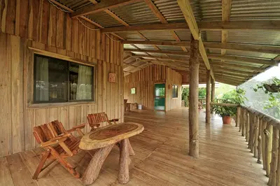a porch of a wooden cabin with a table and chairs at Finca Amistad Cacao Lodge in Bijagua