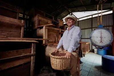 a man holding a basket of food in a barn at Finca Amistad Cacao Lodge in Bijagua