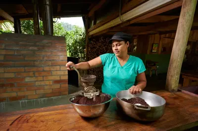 a woman preparing food in two bowls on a table at Finca Amistad Cacao Lodge in Bijagua
