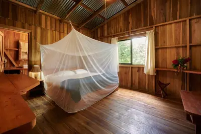 a bed in a room with a mosquito net at Finca Amistad Cacao Lodge in Bijagua