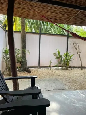 a patio with a chair and a fence and trees at Beach Cabinas in Santa Teresa Beach