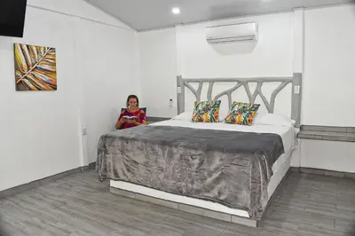 a woman sitting next to a large bed in a room at Tropical Paradise Bungalows in Pital