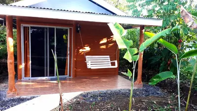 a house with a wooden porch with a chair at Tropical Paradise Bungalows in Pital