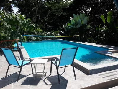 two chairs and a table next to a swimming pool at Tropical Paradise Bungalows in Pital