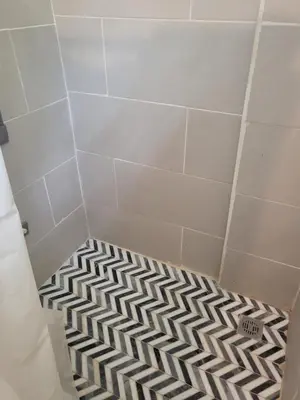 a shower with a black and white tile floor at Pura Vida Condo in Tamarindo