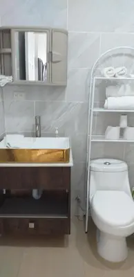 a bathroom with a sink and a toilet and a shelf at Pura Vida Condo in Tamarindo