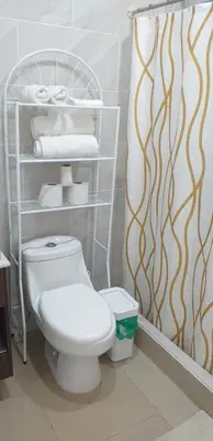 a bathroom with a toilet and a shelf with towels at Pura Vida Condo in Tamarindo