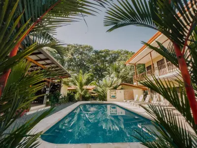 a pool in front of a house with palm trees at Tropical Beach in Uvita