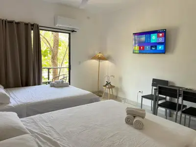 a room with two beds and a tv on the wall at La Jungla in Carrillo