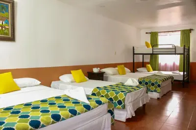 a room with three beds with yellow and blue at Hotel Hacienda del Mar in Carrillo