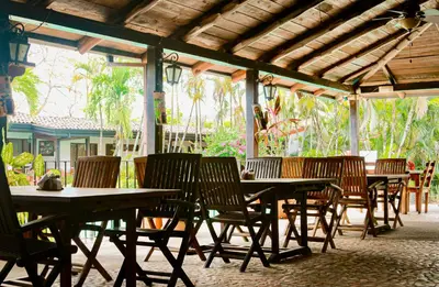 a group of wooden tables and chairs under a pavilion at Hotel Hacienda del Mar in Carrillo