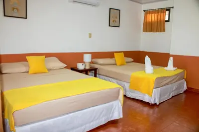 two beds in a room with yellow and white sheets at Hotel Hacienda del Mar in Carrillo