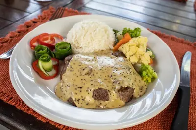 a plate of food with a chicken with rice and vegetables at Hotel Hacienda del Mar in Carrillo