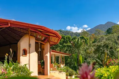 a house with a red roof with mountains in the background at Rio Chirripo in Rivas