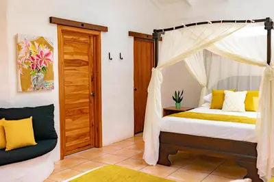 a bedroom with a canopy bed and a chair at Rio Chirripo in Rivas