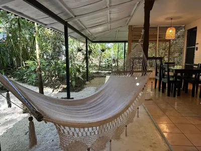 a hammock in a house with a table and chairs at Colibri Apartments - Private kitchen & bathroom - 4 min walk to the Beach! in Santa Teresa Beach
