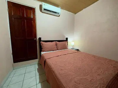 a bedroom with a bed with a red blanket and a door at Casa Quepos in Quepos