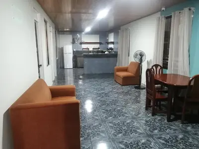 a living room with a table and chairs and a kitchen at Casa Quepos in Quepos