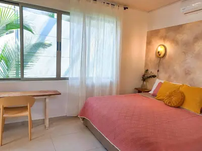 a bedroom with a bed and a desk and a window at Calma Apartments Costa Rica in Mal País
