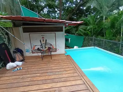 a deck next to a swimming pool with a table and a chair at Burnt Toast Surfcamp in Nosara