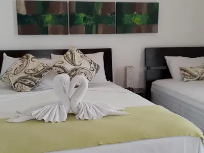 a bedroom with two beds with white sheets and pillows at Las Perlitas Rentals Playa Samara in Sámara