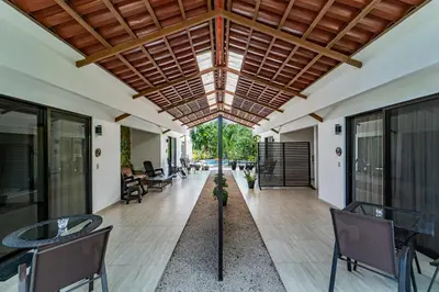 an open lobby with tables and chairs and a ceiling at Las Perlitas Rentals Playa Samara in Sámara
