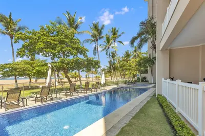 a swimming pool with chairs and the beach at The Palms Jaco in Jacó