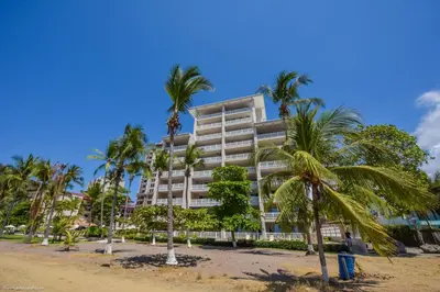 a tall building with palm trees in front of it at The Palms Jaco in Jacó